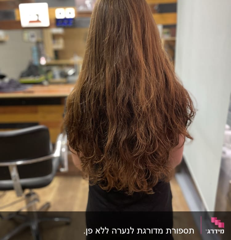 אישה עם שיער ארוך במספרה ליד כיסא ספרים